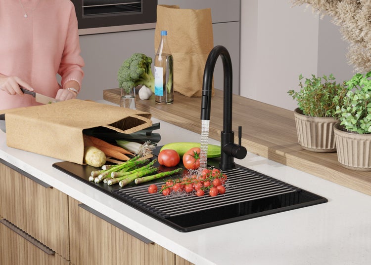 Küche mit Spüle, Armatur, Gemüse und einer Person, die Gemüse schneidet.