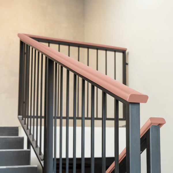 Handlaufprofil aus Kunststoff auf einem modernen Metallgeländer für Treppen im Innenbereich.