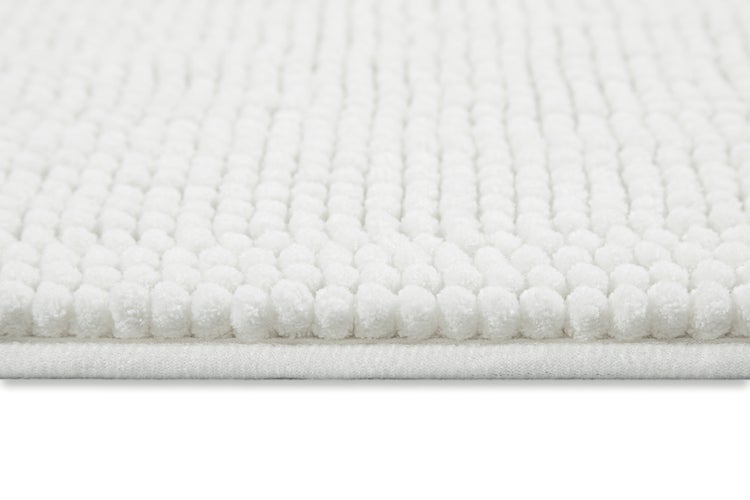 Nahaufnahme einer weißen Chenille-Badematte mit weichen Noppen aus Mikrofaser und eingefasstem Rand.