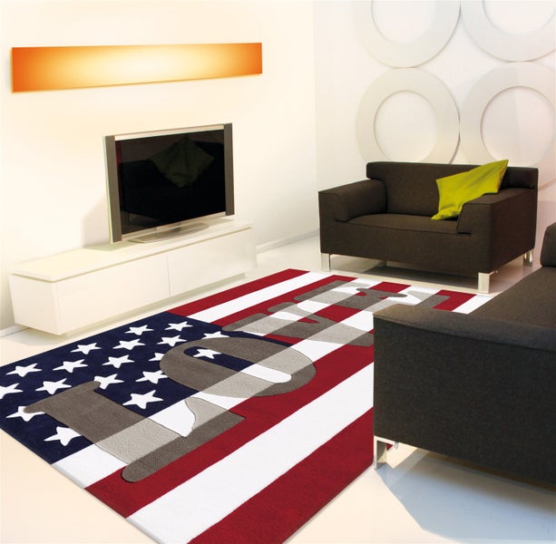 Modernes Wohnzimmer mit Teppich im USA Flaggen Design und LOVE Schriftzug, grauen Sofas und weißem TV Schrank.