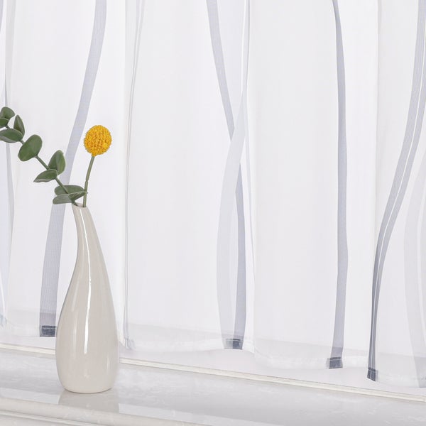Dekoratives Fenster mit transparentem Vorhang mit Streifenmuster und Vase mit Blumen