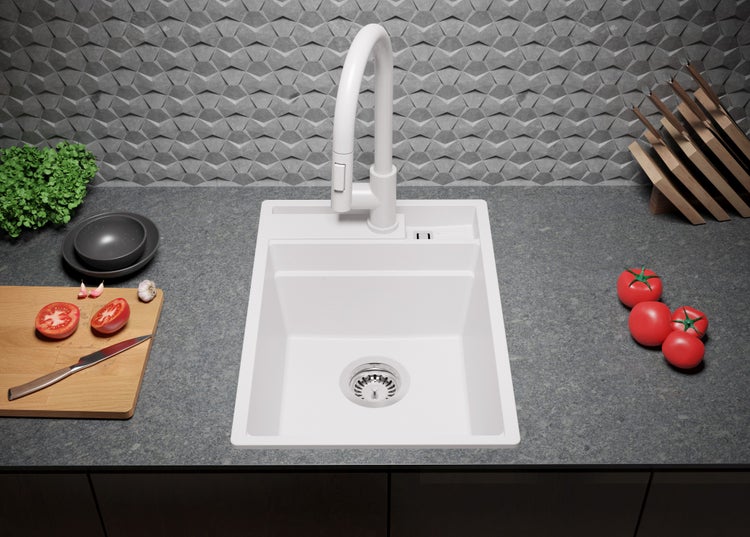 Küchenspüle mit Armatur auf einer Arbeitsplatte mit Lebensmitteln und Küchenutensilien.