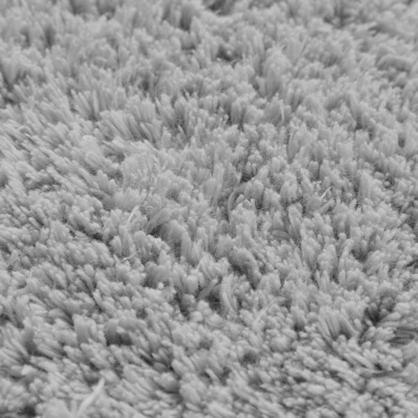 Nahaufnahme der Struktur eines grauen Hochflor-Teppichs mit dichten Fasern.