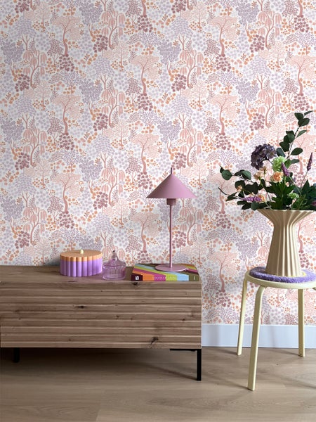 Raumansicht mit Baumtapete, Kommode, Lampe und Blumen