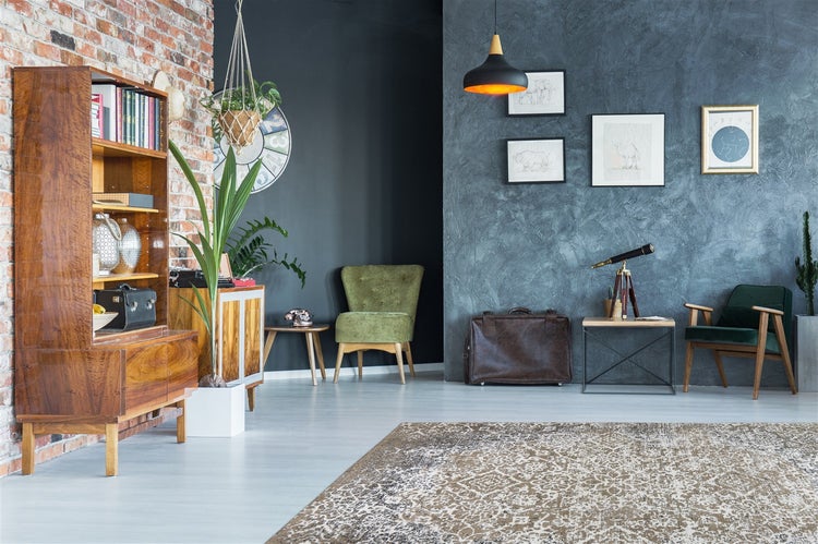 Wohnzimmer mit Backsteinwand, strukturierter Wand, Vintage-Holzmöbeln, gepolsterten Sesseln, Zimmerpflanzen und gemustertem Teppich.