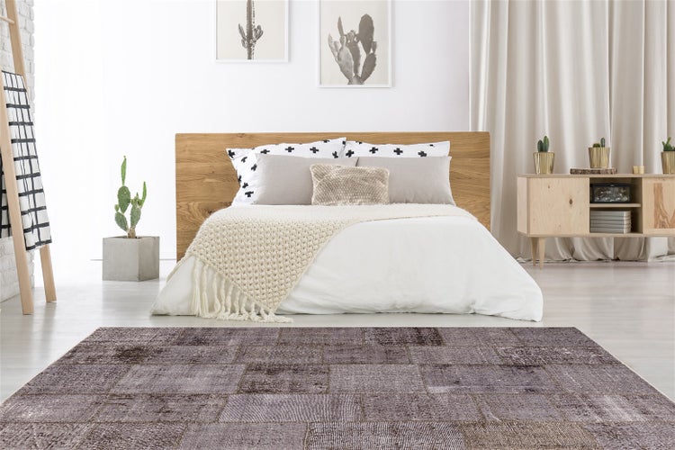 Patchwork-Teppich in Brauntönen in einem hellen Schlafzimmer mit Holzbett und Sideboard.