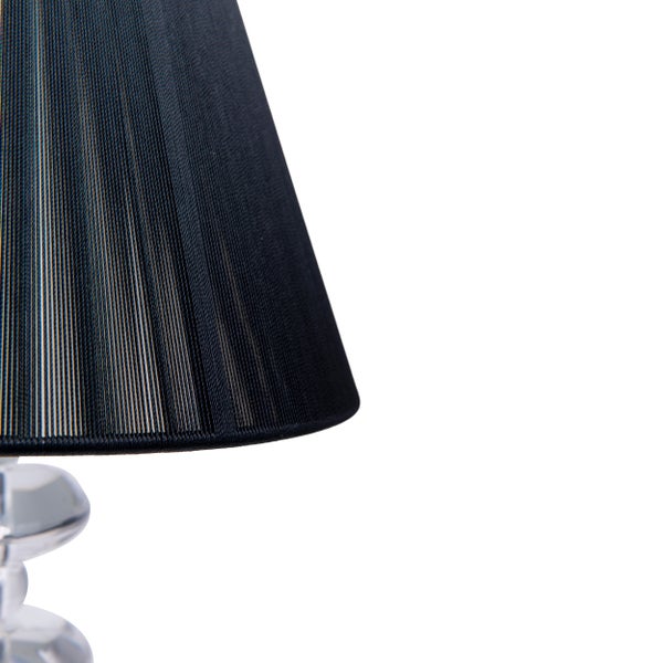 Detailaufnahme einer Tischleuchte mit schwarzem Lampenschirm und transparentem Lampenfuß.