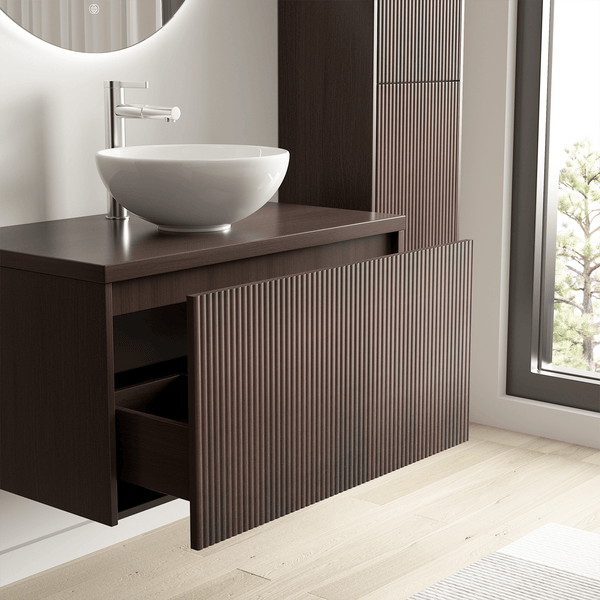 Moderner Waschtischunterschrank in Dunkelbraun mit geriffelter Front und weißem Aufsatzbecken in einem hellen Badezimmer.