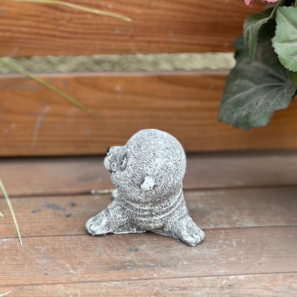 Kleine Gartenfigur Seehund aus Steinguss auf einer Holzterrasse.