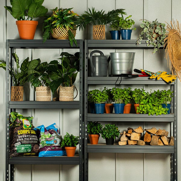 Zwei graue Metallregale mit Pflanzen, Blumentöpfen, Blumenerde, Gießkannen, Gartenwerkzeug und Holz