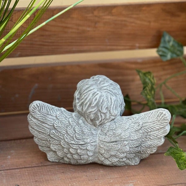 Gartenfigur in Form eines Engels aus Stein in einer hölzernen Umgebung