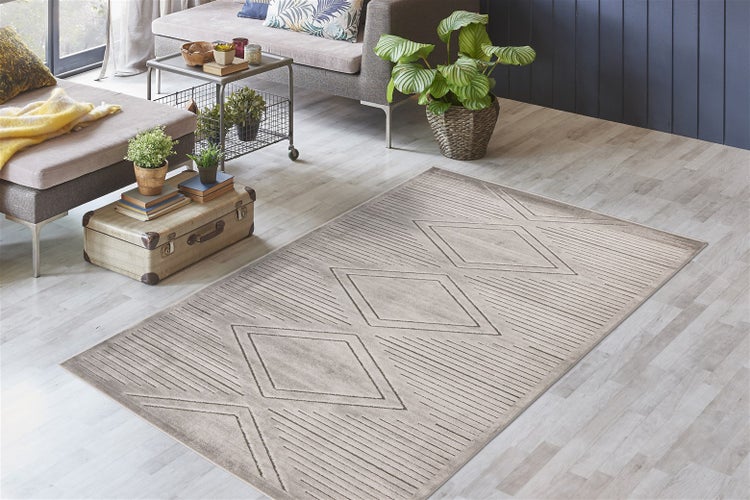 Rechteckiger Teppich mit geometrischem Rauten- und Streifenmuster in einem hellen, modern eingerichteten Wohnzimmer auf Laminatboden.