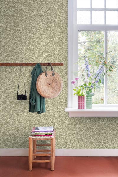 Einladender Raum mit floral gemusterter Tapete, Holzgarderobe, geflochtener Tasche und natürlichem Licht