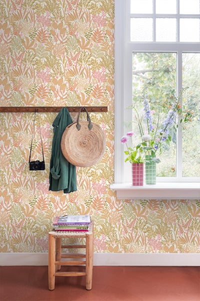 Raum mit floral gemusterter Tapete, Holzgarderobe, Dekorationen und einem Fenster