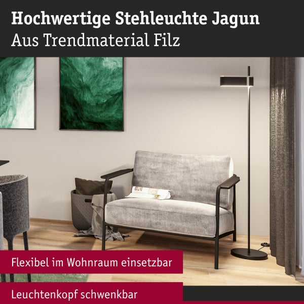 Moderne Stehleuchte Jagun aus Filz mit schwenkbarem Kopf in einem Wohnzimmer neben einem grauen Sessel und Wandbildern.
