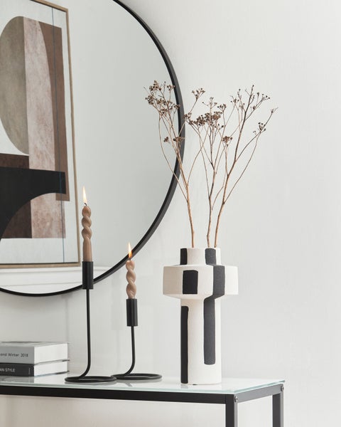 Dekorative Szene mit Kerzen, Vase und Spiegel auf einem Tisch