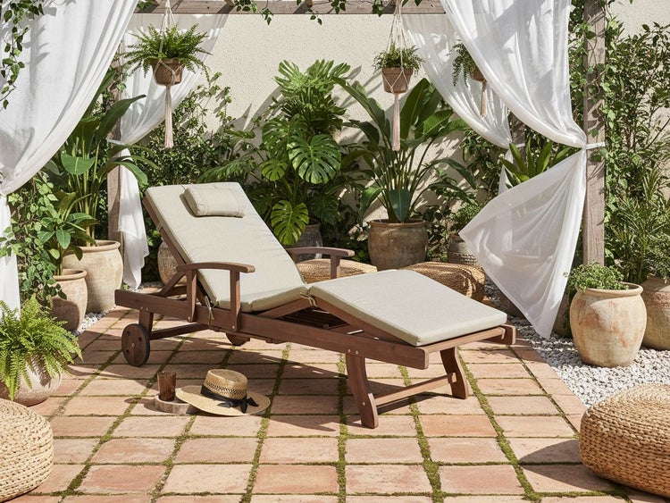 Holzliege mit Polsterauflage im Gartenbereich mit Pflanzen und Dekorationen