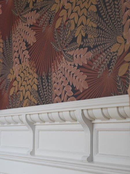 Detailansicht einer Wand mit botanischer Tapete und weißem Ziergesims
