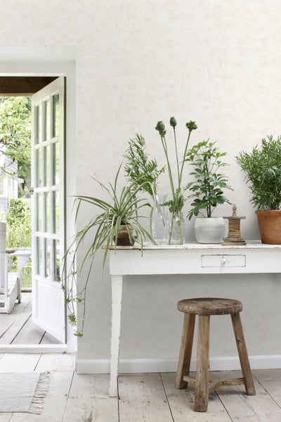 Helle Raumgestaltung mit Vintage-Tisch, Zimmerpflanzen und Holzhocker