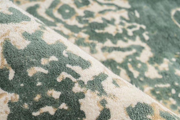 Nahaufnahme eines weichen gemusterten Teppichs mit abstraktem marmoriertem Design in Grün- und Cremetönen.