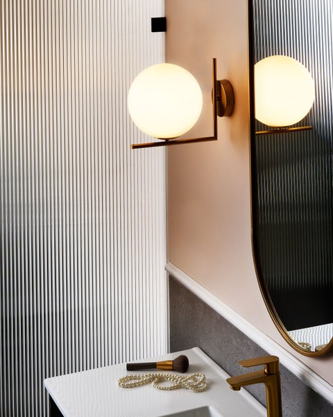 Modernes Badezimmer mit Wandleuchte, Spiegel, Waschbecken und Accessoires