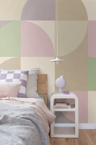 Schlafzimmer mit Bett, Nachttisch und geometrischer Tapete