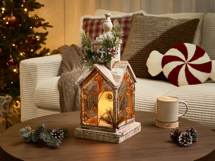 Dekorative Laterne im Hausdesign mit Kerze und Tannenzweigen für die Weihnachtszeit