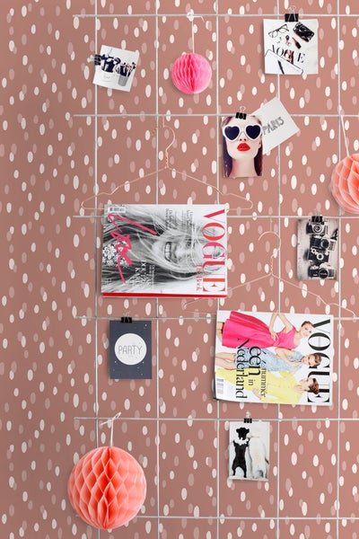 Wanddekoration mit Fotos, Magazinen und Papierdekorationen an Metallgitter aufgehängt