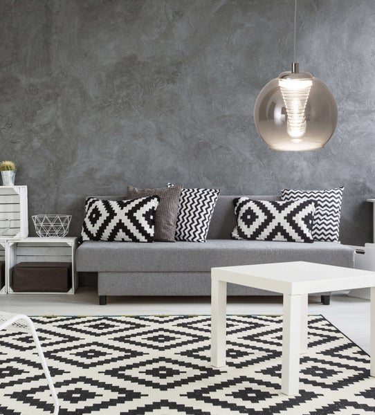 Wohnzimmer mit Sofa, Kissen, Tisch und Teppich im modernen Design