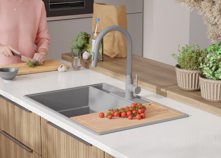 Küchenspüle mit Abtropffläche, Armatur, Schneidebrett mit Tomaten und Person, die Kräuter schneidet