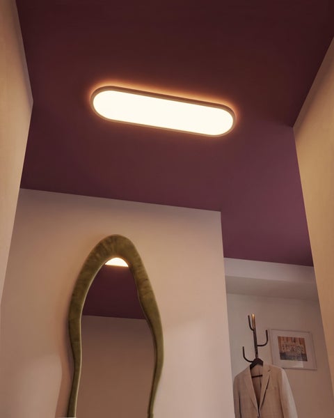 Moderne LED Deckenleuchte in ovaler Form in einem stilvoll eingerichteten Flur mit Spiegel und Garderobe.