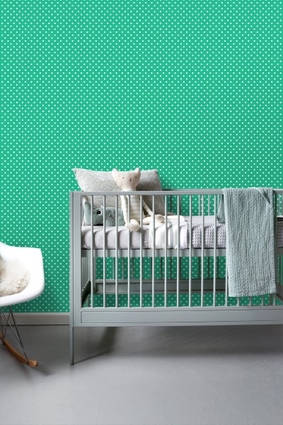 Kinderzimmer mit gepunkteter Tapete, Babybett und Schaukelstuhl