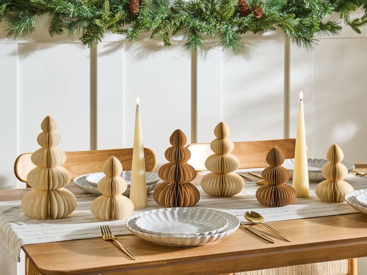 Festlich gedeckter Tisch mit Pappfiguren in Baumform und Kerzen