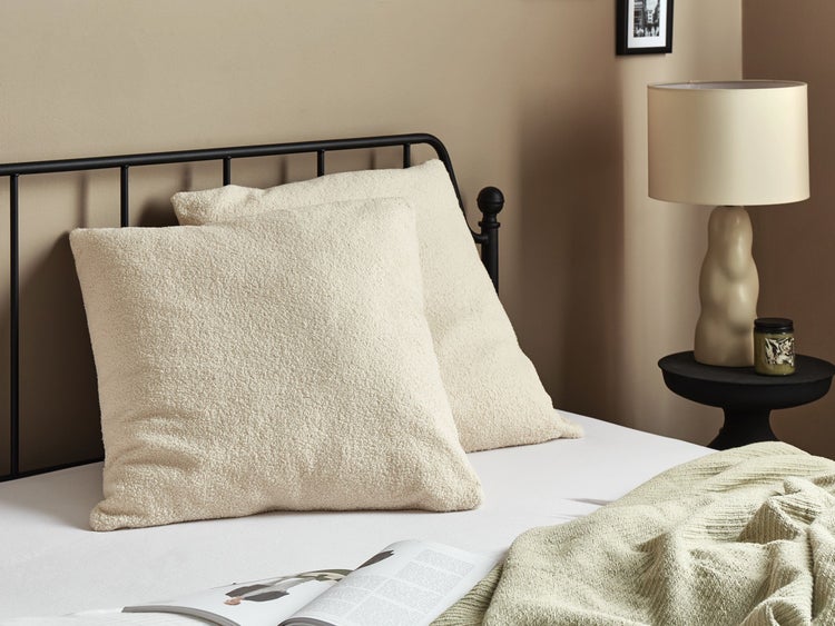 Dekorative Kissen auf einem Bett mit schwarzem Metallrahmen