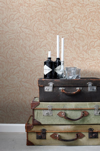 Dekorative Szene mit floraler Tapete und gestapelten Vintage-Reisekoffern