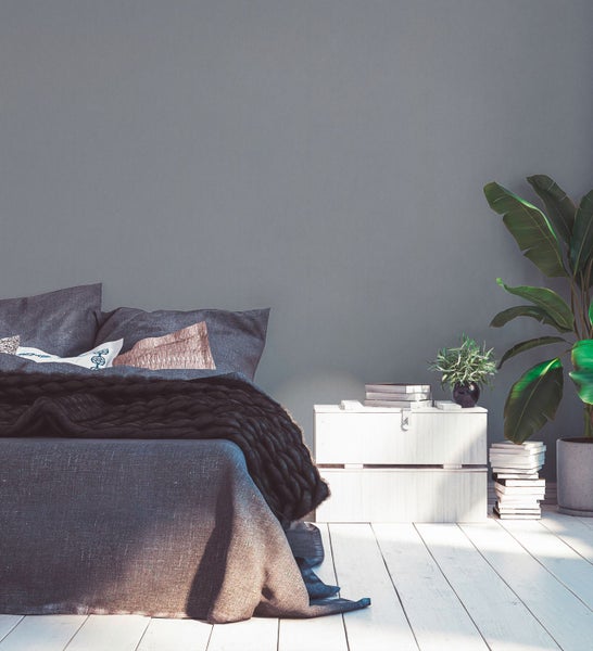 Wohnzimmer mit Sessel, Kommode, Lampe und Büchern