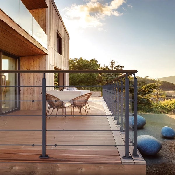 Moderne Holzterrasse mit Geländer aus Metallpfosten, waagerechten Drahtseilen und einem Handlauf aus Holz.