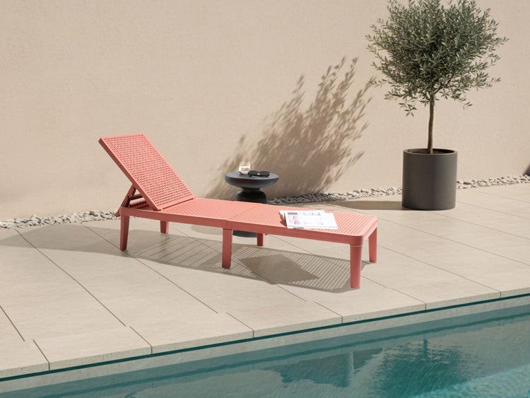 Liegestuhl aus Kunststoff neben einem Pool