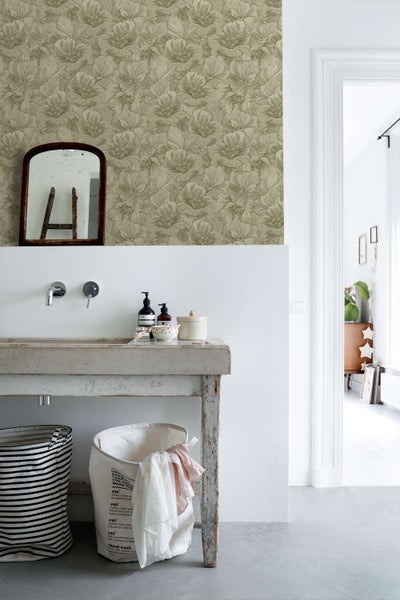 Badezimmer mit Blumen-Tapete an der Wand, Waschbecken aus Stein auf einem Holztisch, Spiegel, zwei Wäschekörbe und Blick in den angrenzenden Raum.