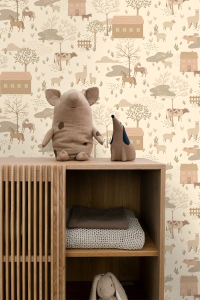 Tapete mit Bauernhoftieren und Häusern im Kinderzimmer über einem Holzschrank mit Spielzeug