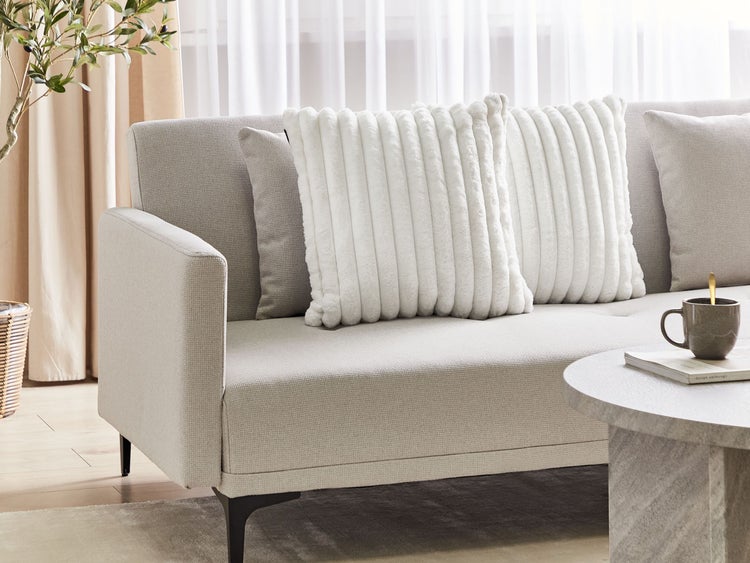 Helles Wohnzimmer mit Sofa, Kissen und Tisch