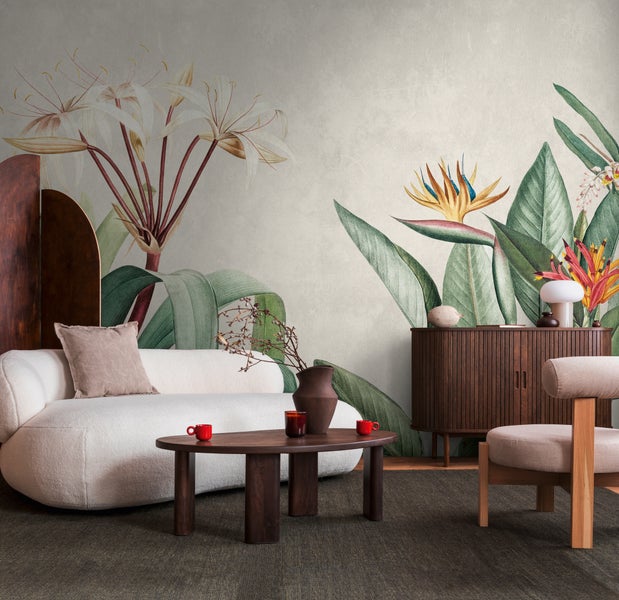 Wohnzimmer mit botanischer Fototapete mit großen tropischen Blumen und Blättern, weißem Sofa und dunklen Holzmöbeln.