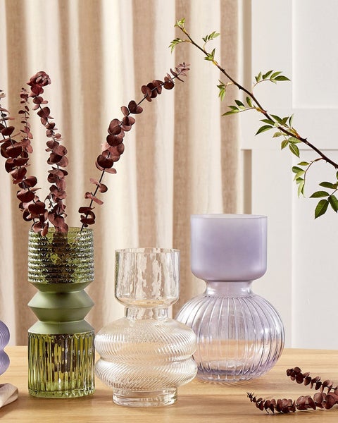 Drei dekorative Glasvasen mit Pflanzen auf einem Tisch