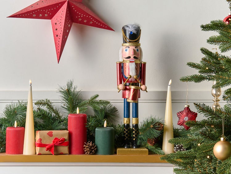 Weihnachtliche Dekoration mit Nussknacker, Stern, Kerzen und Geschenk