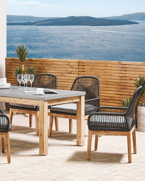 Gartensitzgruppe mit Tisch und Stühlen auf einer Terrasse mit Meerblick