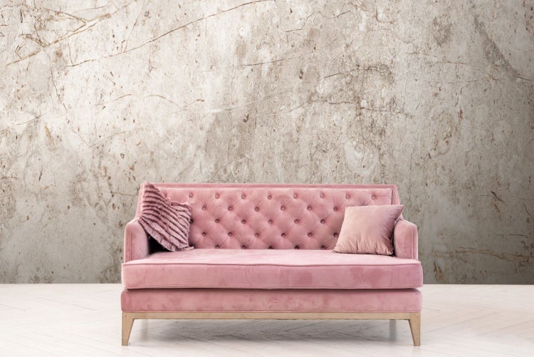 Rosa Sofa mit zwei Kissen vor einer Marmorwand