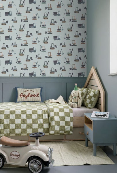 Vliestapete mit Baustellenfahrzeugen im Kinderzimmer über blauer Wandvertäfelung, Bett in Hausform und Spielzeugauto.