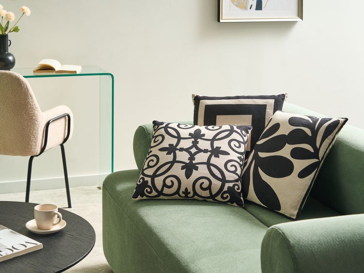 Wohnzimmer mit Sofa, Kissen mit Mustern, Tisch und Stuhl