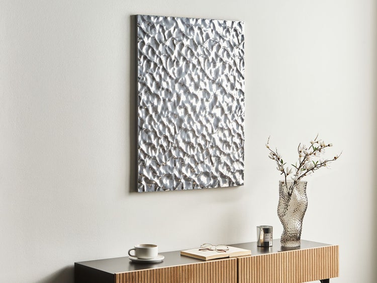 Szene mit silberfarbenem Wandbild, dekorativer Vase und Möbeln