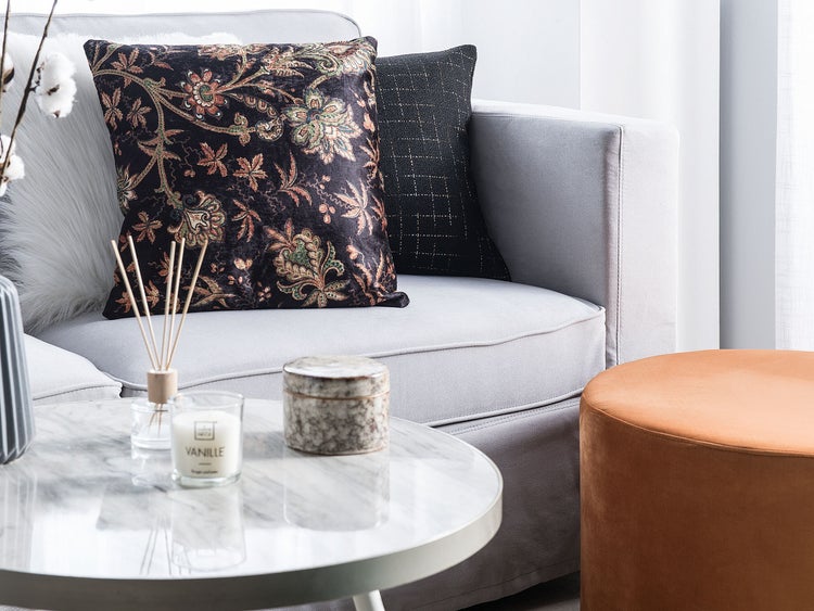 Wohnzimmer mit Sofa, Zierkissen, Couchtisch und Hocker